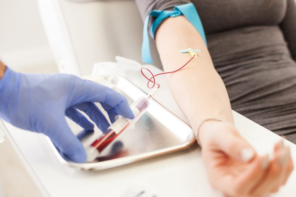 a healthcare worker draws blood from a patient's right arm 
